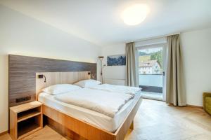 a bedroom with a large bed and a large window at Harmls Aparthotel in Flachau