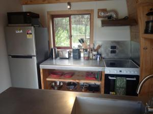 a kitchen with a refrigerator and a counter top at Private cozy timber chalet with fireplace in Raglan
