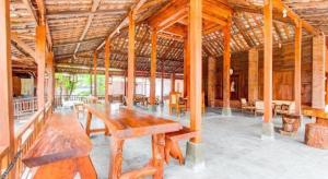 a large wooden pavilion with wooden tables and benches at Capital O 93873 Sokkyo Homestay in Ngemplak