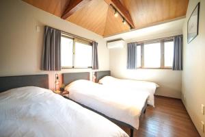 zwei Betten in einem Zimmer mit zwei Fenstern in der Unterkunft Route 99 Sengokuhara in Sengokuhara