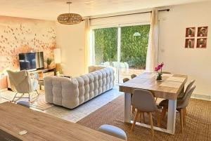 a living room with a couch and a table with chairs at Maison cosy avec SPA privatif à 13 min du Futuroscope in Beaumont