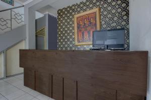 eine Rezeption mit TV darüber in der Unterkunft Hotel O Near Tugu Yogyakarta 1 formerly Crown Residence in Jetis