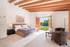 a bedroom with a bed and a chair and a window at Can Perot - Pollença in Pollença +29 photos