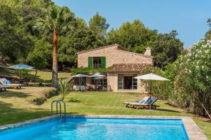 a house with a swimming pool in front of a yard at Can Perot - Pollença in Pollença