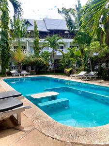 een groot zwembad met stoelen en een gebouw bij Elala Studio Homes in Diani Beach