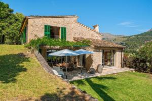an external view of a stone house with umbrellas at Can Perot - Pollença in Pollença