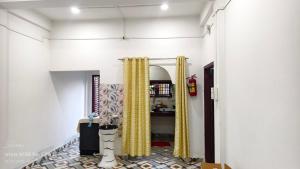 Un pasillo con cortinas amarillas en una habitación blanca. en Shaan's Homestay, en Jorhat