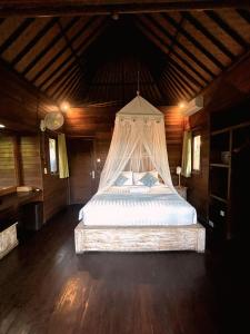 un lit à baldaquin dans une chambre en bois dans l'établissement Island Cabanas Formerly Taman Sari Villa, à Nusa Lembongan