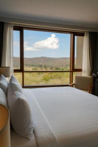 a bedroom with a large bed and a large window at Wellworth Mikumi Wildlife Lodge in Morogoro