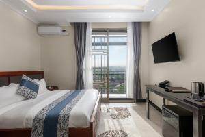 a hotel room with a bed and a desk and a window at Beal Mall & Hotel in Arua