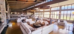 a large room with white couches and tables and windows at Wellworth Mikumi Wildlife Lodge in Morogoro +3 photos