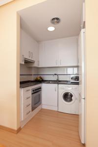 cocina con armarios blancos, lavadora y secadora en Apartamentos Port Cambrils en Cambrils