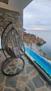 een stoel op een balkon met uitzicht op de oceaan bij The Cliff Residences in Melínta
