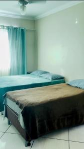 two beds sitting in a bedroom with a window at Suíte férias in Cabo Frio