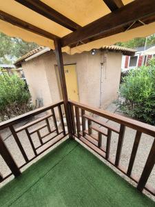a balcony with a wooden fence and a door at Vias plage "MER & SOLEIL" Mobil home camping La Carabasse 6 a 8 personnes in Vias
