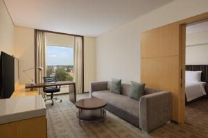a hotel room with a couch and a desk and a bed at Courtyard by Marriott Bilaspur in Bilāspur