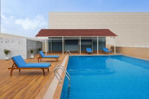 a swimming pool with two blue chairs next to a building at Courtyard by Marriott Bilaspur in Bilāspur