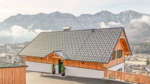 ein Haus mit einem Dach mit Bergen im Hintergrund in der Unterkunft Sunleitn-Residenz in Bad Goisern