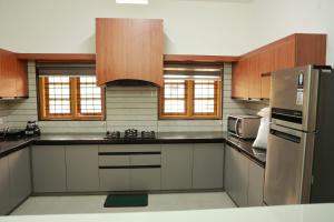 a large kitchen with wooden cabinets and stainless steel appliances at Rain Drops Homestay in Anachal