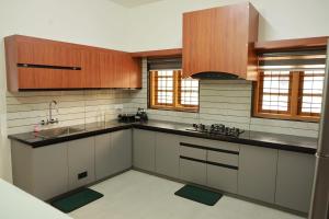 a kitchen with white counters and wooden cabinets at Rain Drops Homestay in Anachal