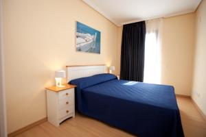 カンブリルスにあるApartamentos Port Cambrilsの青いベッドと窓のある寝室