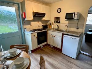een keuken met witte kasten en een tafel met stoelen bij Balcarres Self Catering in Fort William