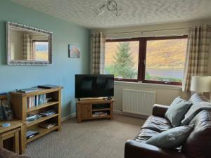 een woonkamer met een bank en een televisie bij Balcarres Self Catering in Fort William