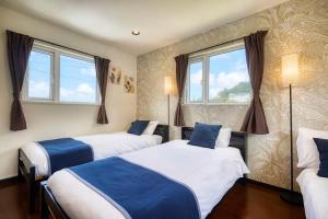 deux lits dans une chambre avec deux fenêtres dans l'établissement CODE ROOMS OKINAWA 今帰仁の貸切宿 チェックイン13時から可 チェックアウト12時まで BBQと自然を満喫 美ら海水族館 ジャングリア沖縄まで車で20分 最大8名ok, à Nakijin