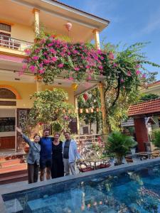 a group of people standing in front of a house with a swimming pool at Tam Coc Family Hotel in Ninh Binh