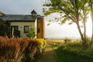 a white house with a tree and a fence at Landal Whitbarrow in Penruddock