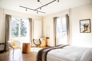 a bedroom with a bed and two chairs and windows at Kurhaus Lenzerheide in Lenzerheide +140 photos