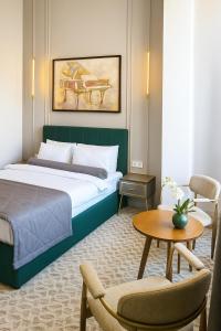 ein Schlafzimmer mit einem Bett, einem Tisch und Stühlen in der Unterkunft The Address by Maestro in Baku