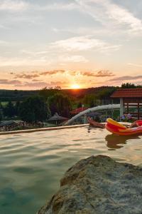 a pool with two boats in the water at sunset at Egri Korona Borház és Wellness Hotel in Demjén
