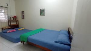 two beds in a room with blue sheets at HEAWOOD GUEST HOUSE Sungai Siput in Sungai Siput