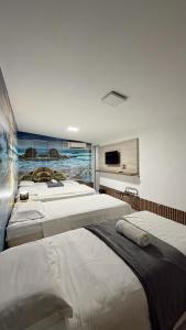 um quarto com quatro camas e uma TV na parede em Casa da Keka em Noronha em Fernando de Noronha