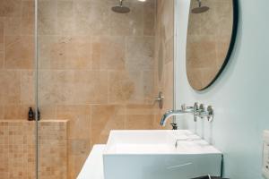 a bathroom with a sink and a shower at The Village Suites in Windhoek +18 photos