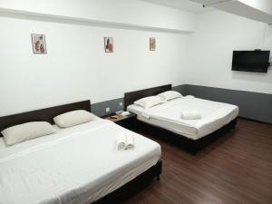 two beds in a hotel room with a tv at SO Hotel in George Town