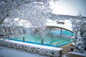 a swimming pool covered in snow with a bridge at Termálfürdő Apartman Igal -130 méterre a fürdőtől in Igal