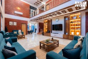 a living room with blue couches and a tv at StayVista at The Red Creek with BBQ and Bonfire in Nagothna