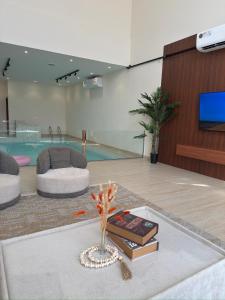 Una sala de estar con una mesa con libros y un televisor. en Roma chalet استراحة روما بدية, en Al Raka