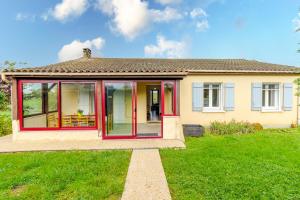 a house with red doors on a green yard at La Maison de Reta - House avec piscine privée in Rouffignac Saint-Cernin