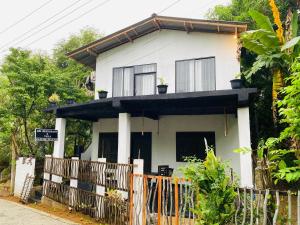 a white house with a fence in front of it at Abi Restaurant & Villa in Tangalle