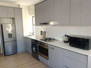 a kitchen with a stove and a microwave at Simons Town long beach Penthouse in Simonʼs Town