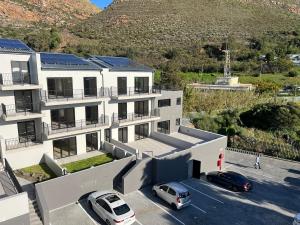 an apartment building with cars parked in a parking lot at Simons Town long beach Penthouse in Simonʼs Town
