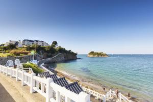 a beach with blue and white chairs and the ocean at Joli duplex a Saint-Quay a deux pas de la plage in Saint-Quay-Portrieux