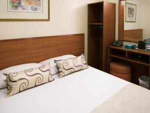 a bedroom with a white bed with a wooden headboard at Hotel 81 Geylang in Singapore