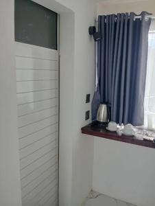 塞姆博伦拉旺Villa Miradarma的一扇挂着蓝色窗帘的窗户，窗台上放着杯子。