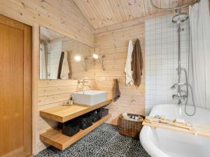 a bathroom with wooden walls and a tub and a sink at Family Cabin With Hot Tub In Hønedalen in Haugen +32 photos