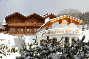 a large wooden building with snow on the ground at Musik - und Wellnesshotel Mariandl Singender Wirt in Haibach