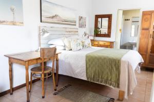 um quarto com uma cama, uma mesa e uma escrivaninha em LA Guesthouse em Piet Retief